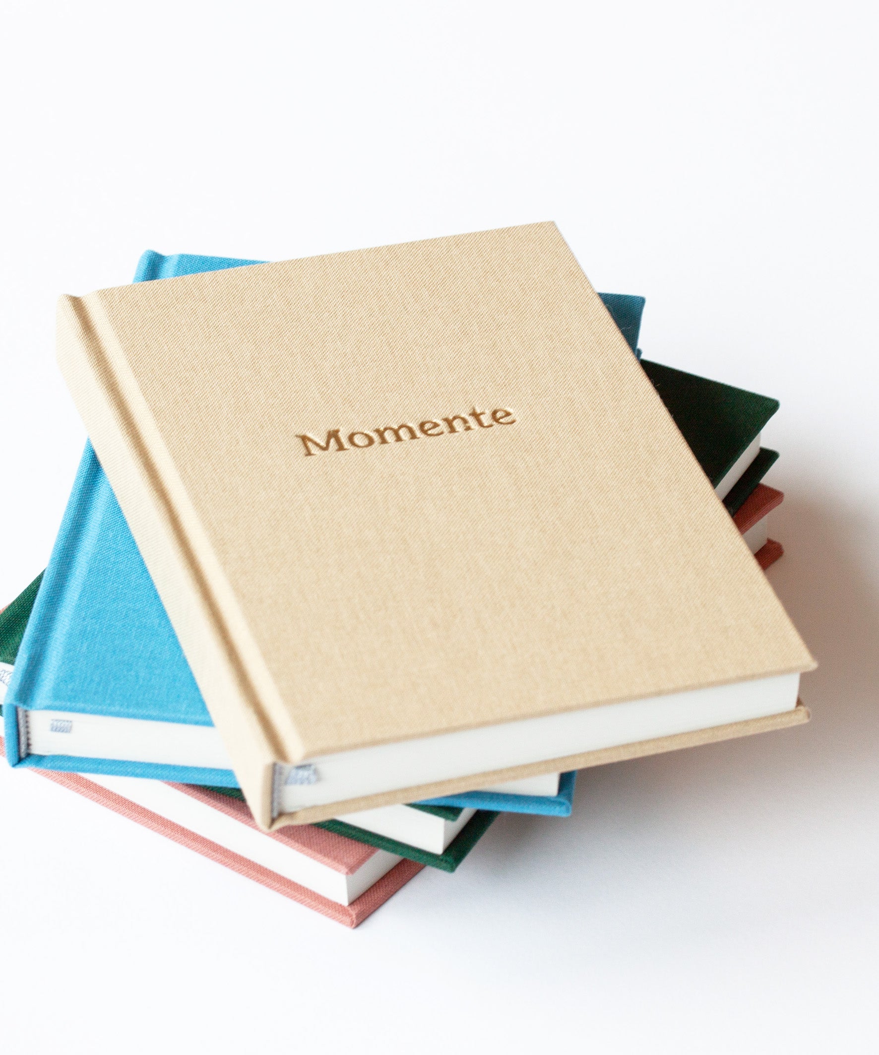 Hochwertiges Momente Erinnerungsbuch  mit Leineneinband gestapelt, alle Titel, und Goldprägung, beige