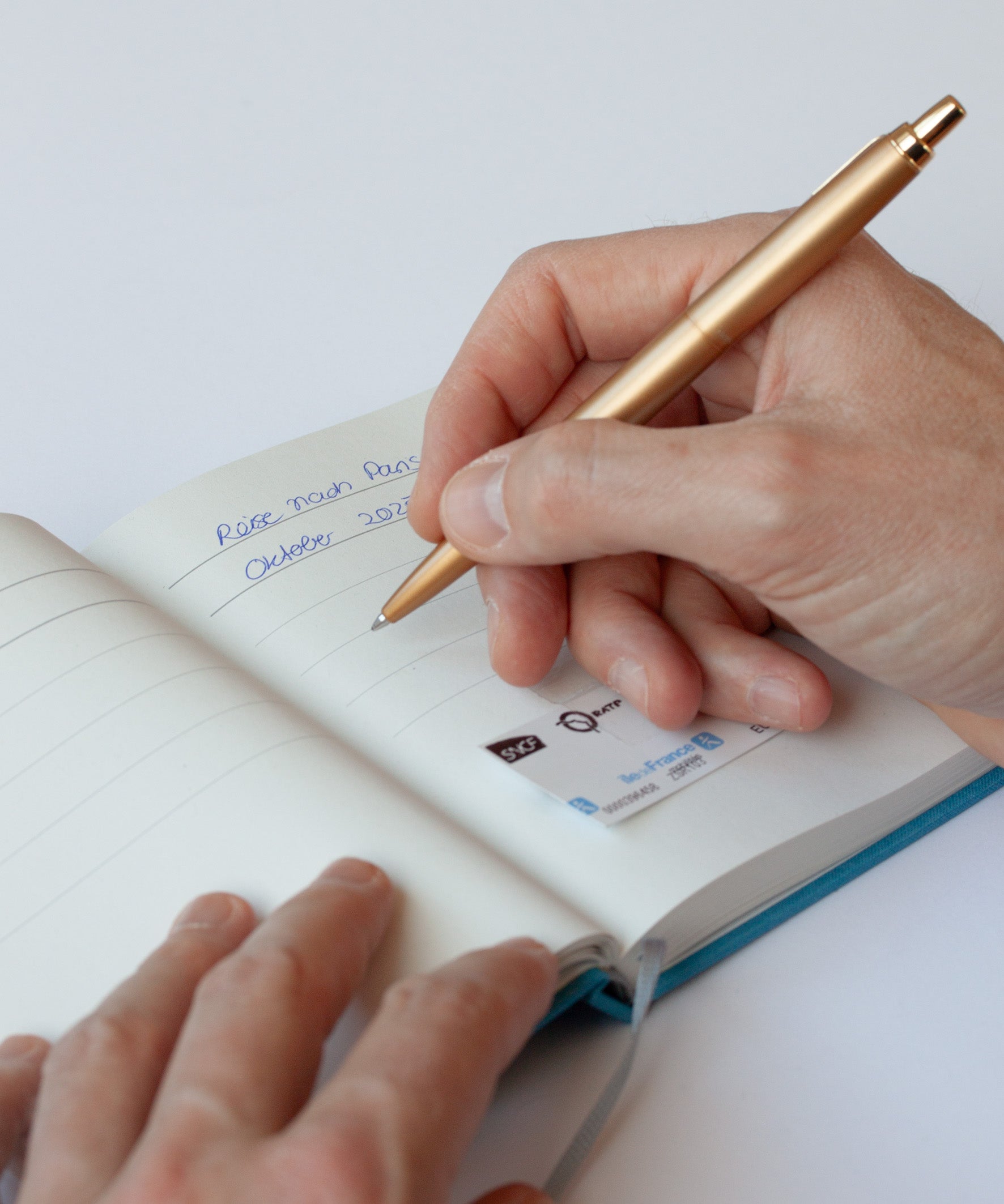 Momente Erinnerungsbuch, aufgeschlagen, Hand schreibt in Buch mit Kugelschreiber, blau