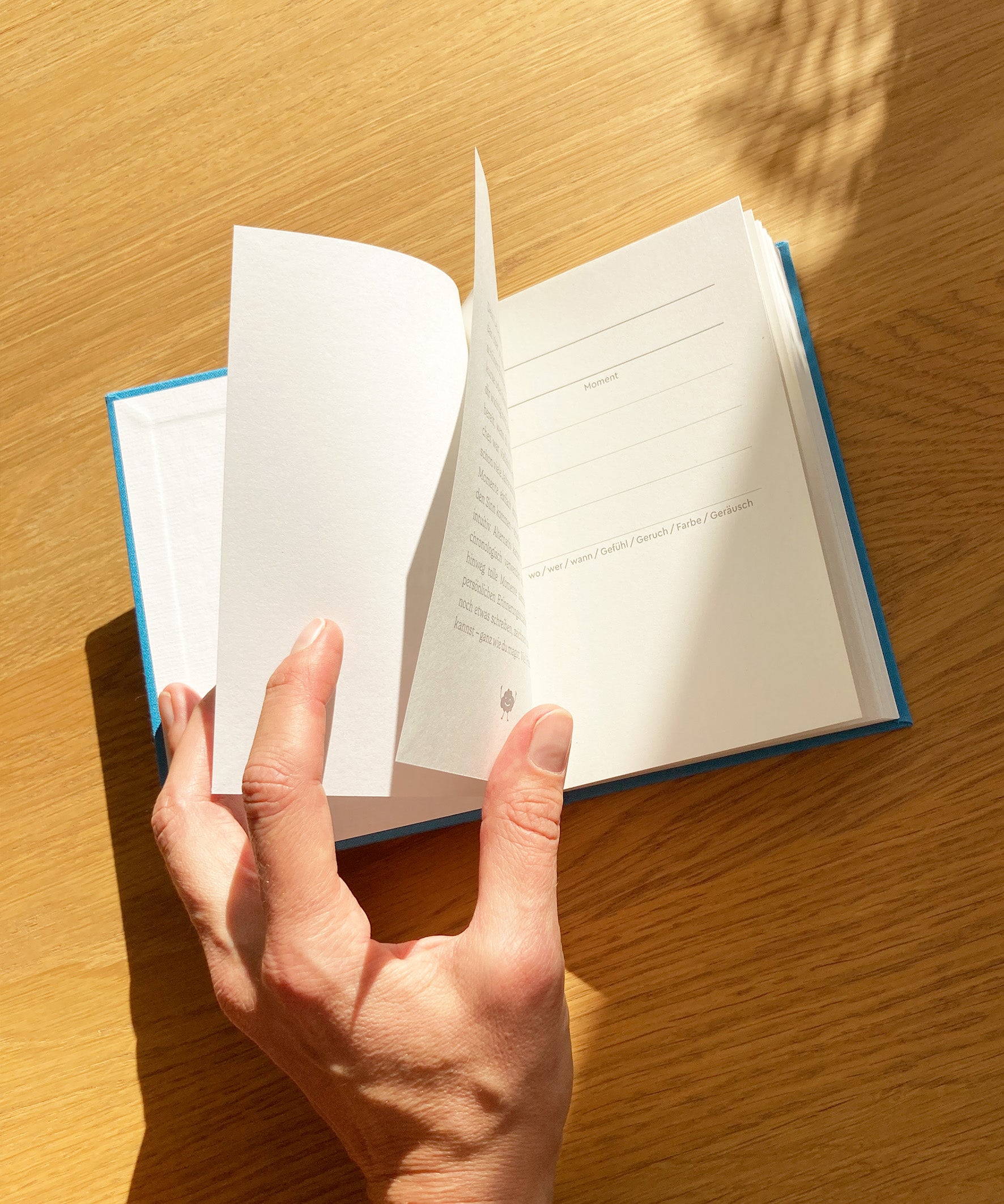 Momente Erinnerungsbuch  mit Leineneinband aufgeschlagen mit Hand, Innenseiten, blau, liniert